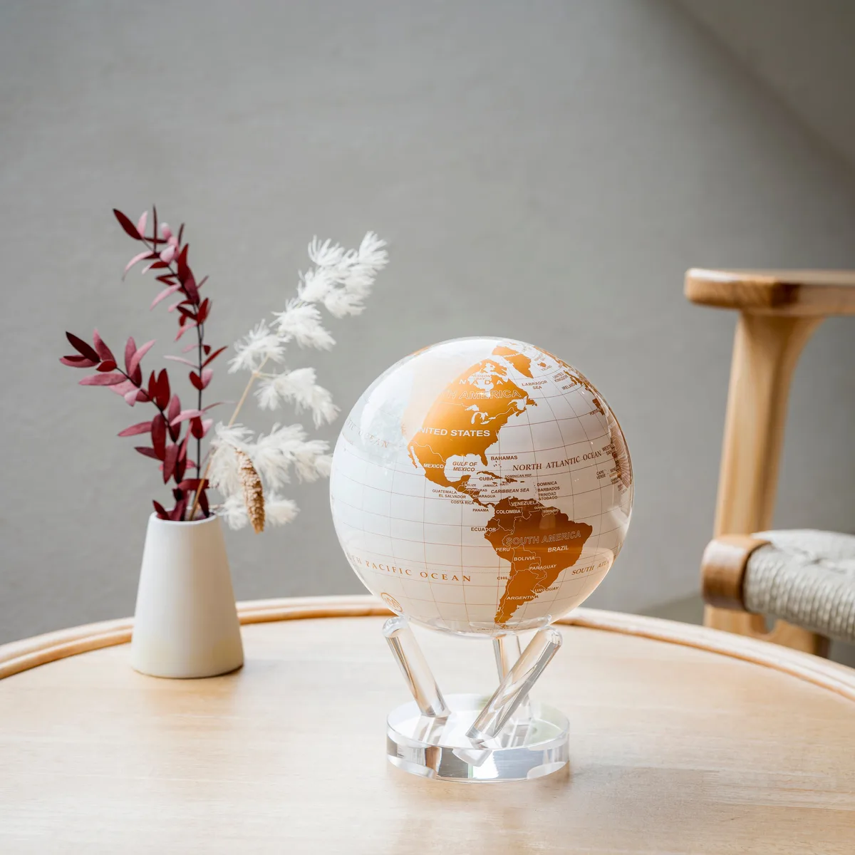 Globe Mova Blanc perle et or posé sur une table avec des fleurs séchées