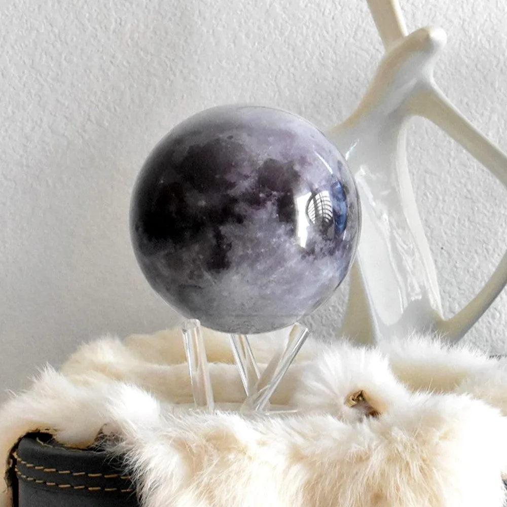 Globe Mova Lune posé sur un meuble, avec un objet décoratif en arrière-plan