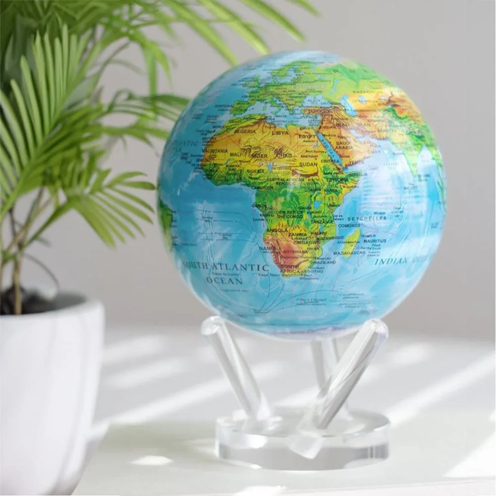 Globe Mova Terre en relief sur un support transparent, près d'une plante verte