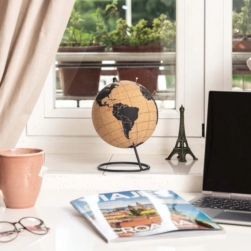 Globe en liège avec épingles de couleur posé sur un rebord de fenêtre