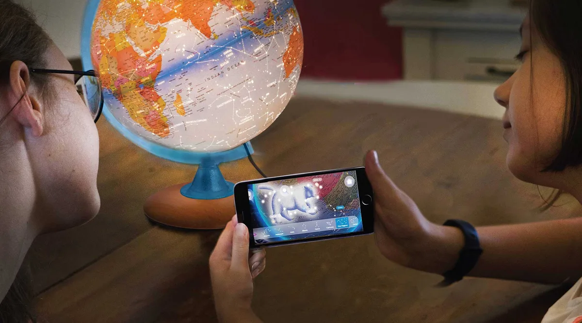 Enfants regardant le globe Constellation Plus avec un smartphone