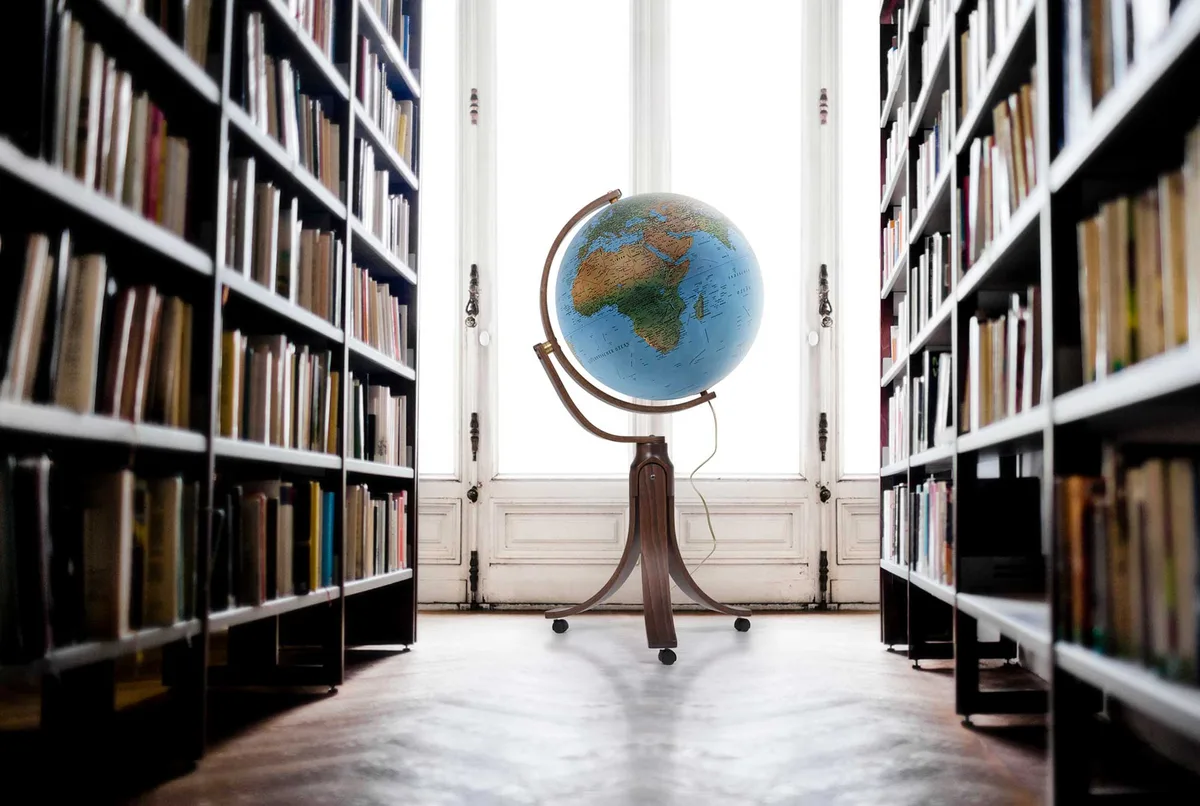 Globe sur pied Räthgloben DP 50 60 posé dans une pièce entre des étagères de livres