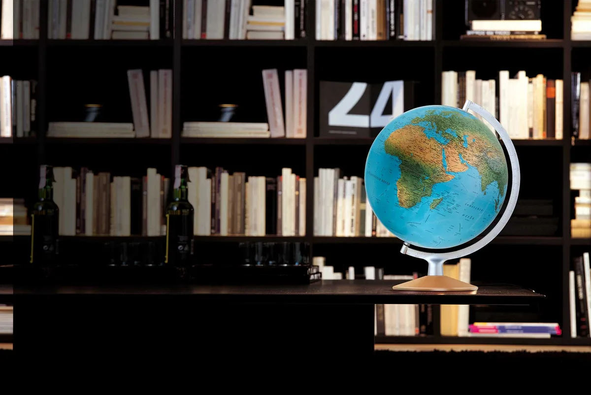 Globe Räthgloben DPI 30 17 posé dans une pièce sombre devant des étagères de livres